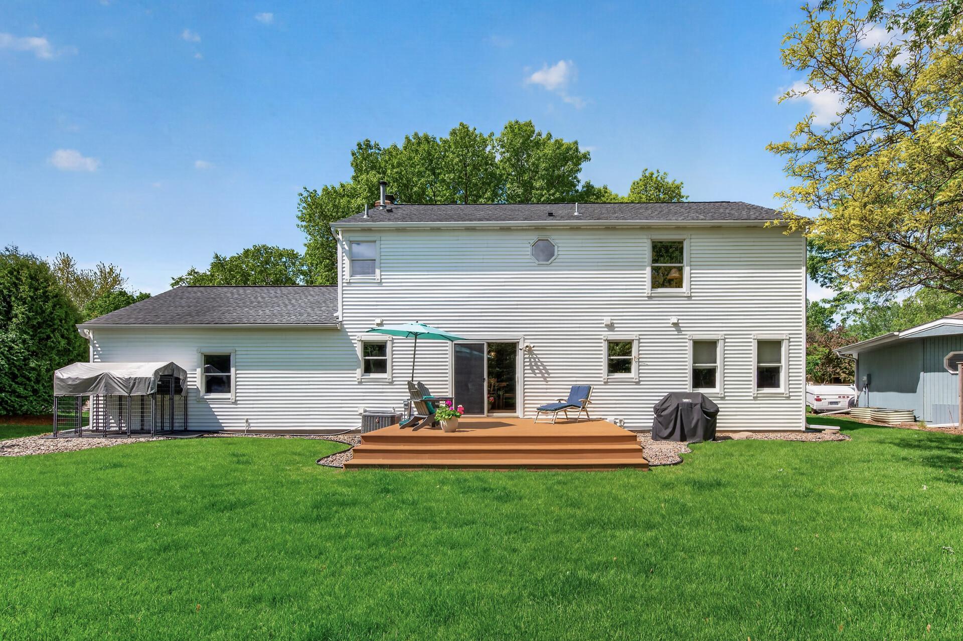 Full rear elevation highlighting the large backyard, maintenance-free deck, and mature tree-lined lot