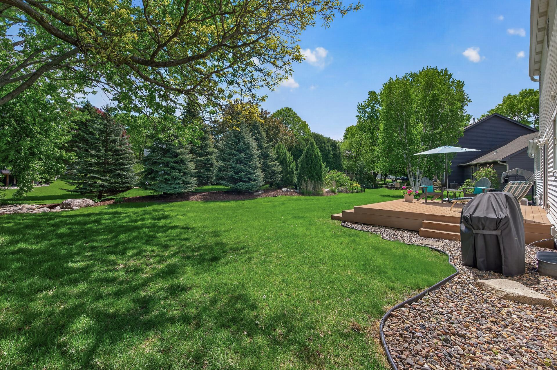 Beautifully landscaped backyard with mature trees, lush lawn, and private outdoor living spaces.