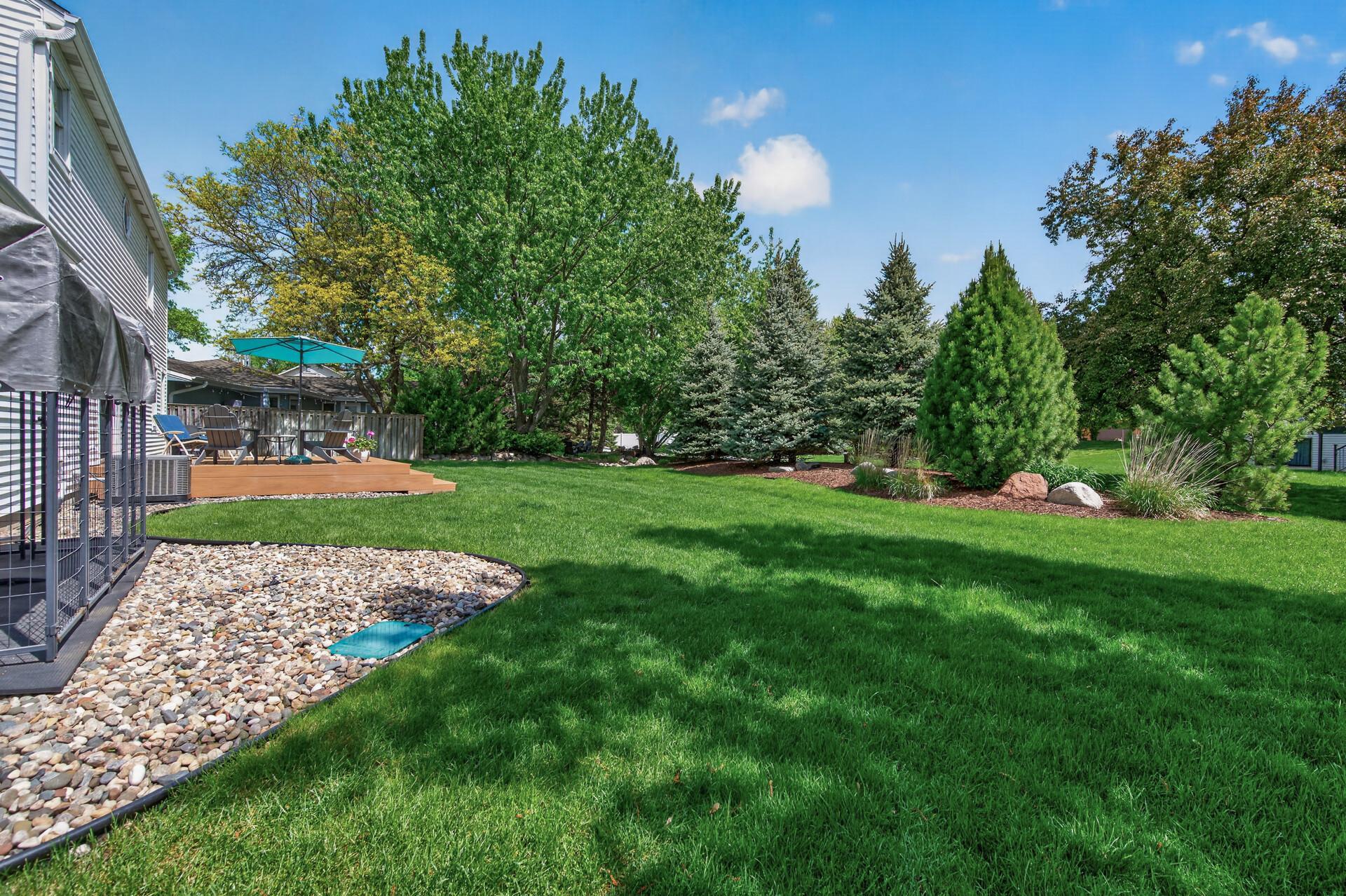 Serene backyard setting with bermed plantings, manicured landscaping and plenty of room to play or entertain.