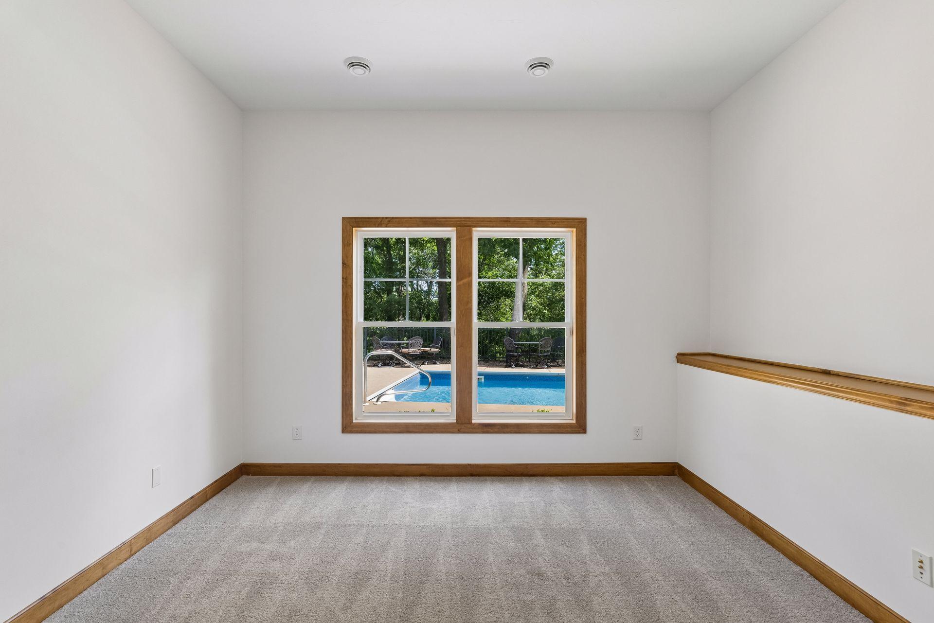 Lower level bedroom with tall ceilings, and a view overlooking the pool. Brand new carpet in this room.