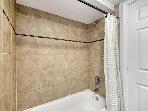 The bathroom features a beautifully tiled tub/shower surround.