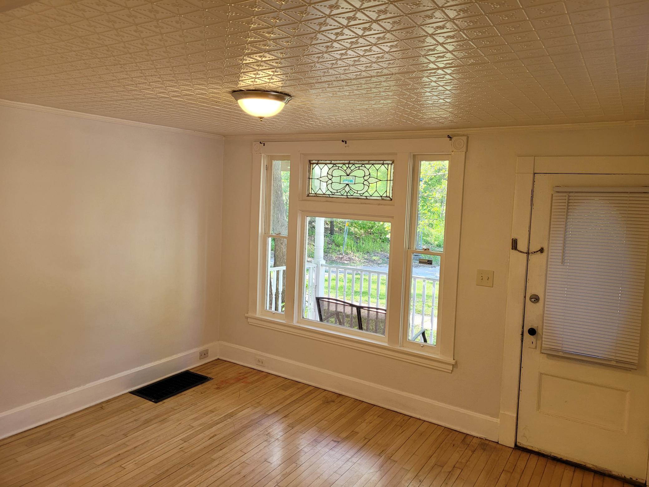 Living room has gorgeous hardwood floors, leaded window and tin ceiling!