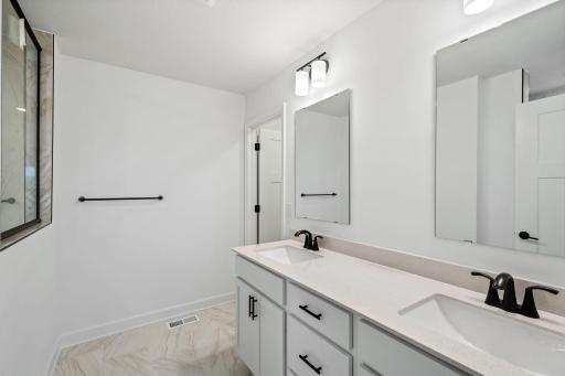 Quartz countertops, plate-glass mirrors, raised-height cabinets and Moen® Glyde faucets unite at this oversized vanity