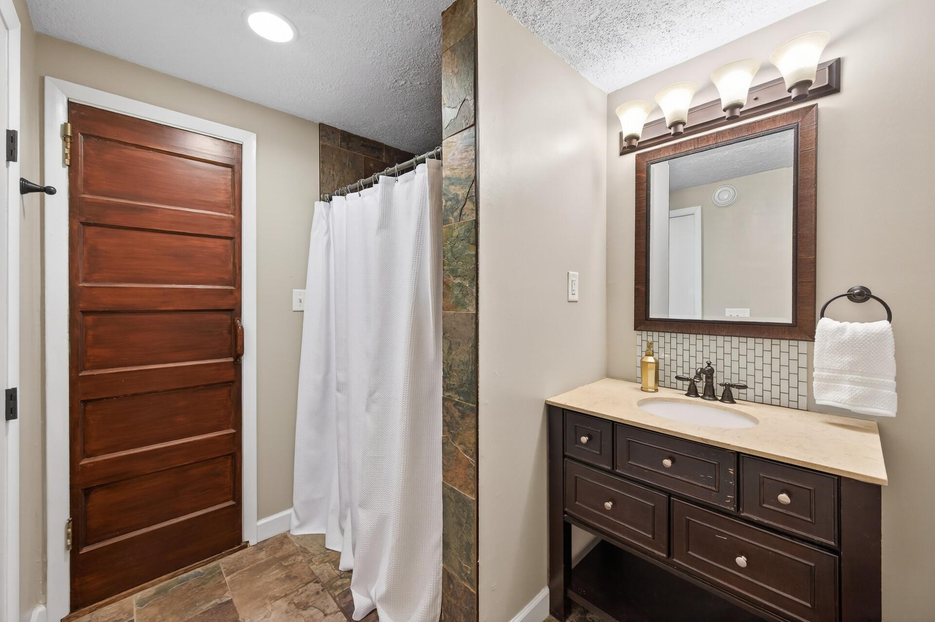 The lower level bathroom includes a tiled walk-in shower, plenty of storage, and access to the sauna.