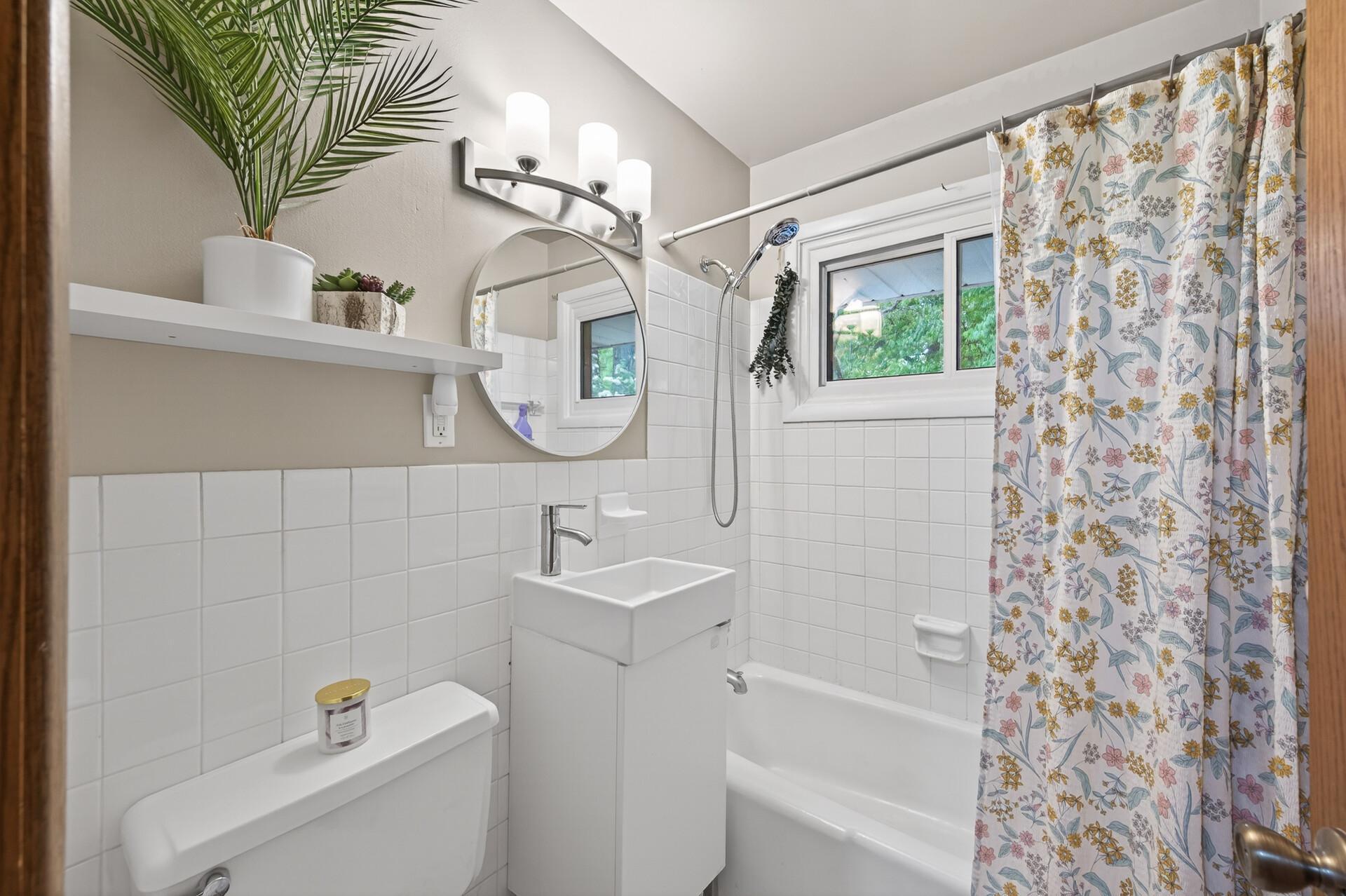 The bright, meticulously maintained full bathroom on the main floor features tiled walls and floors.
