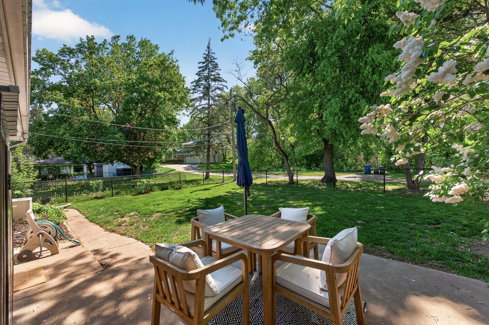 The spacious, fully-fenced backyard features a patio and mature trees.