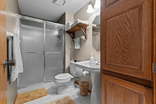 Lower Level bath with ceramic tile floor, wide glass shower and pedestal sink