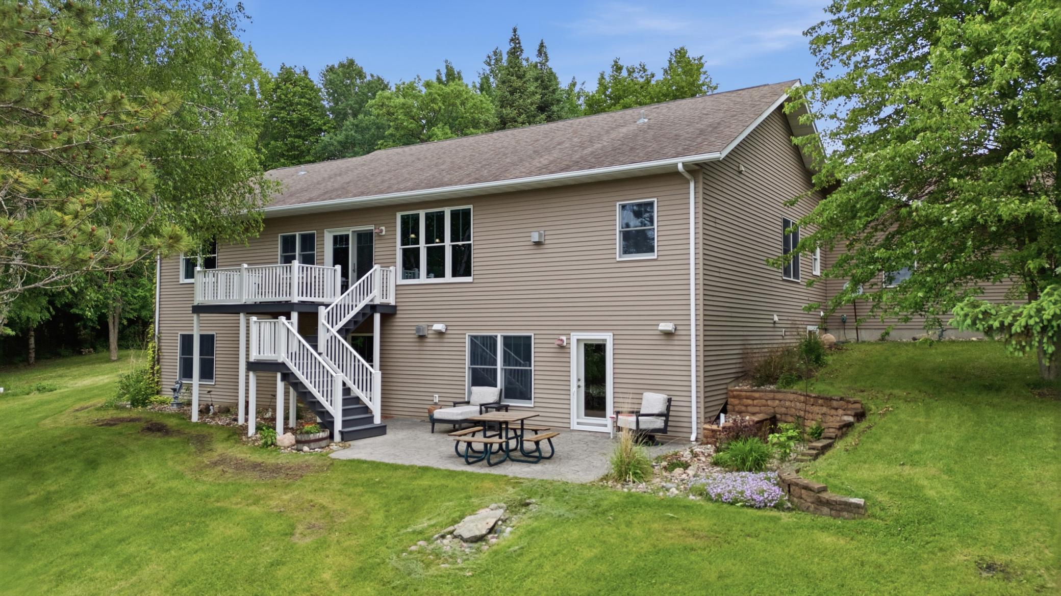 Rear view of Home to Lake (patio, deck, landscaping, walkout from lower level living and from kitchen)