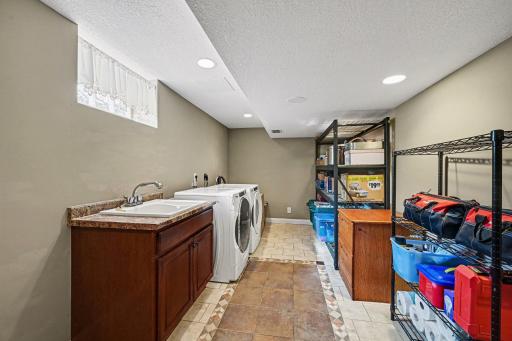 Clean, bright & updated! The spacious laundry room includes Whirlpool front load washer & dryer, utility sink w/storage, ceramic tile floors, knock-down ceiling with recessed lights, a brand-new sump pump & a large folding counter with extra storage.