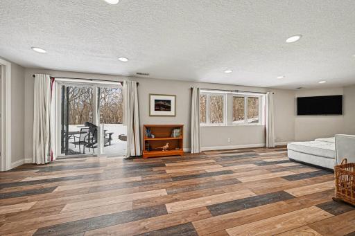 See the beauty for yourself! This perspective showcases the lovely flooring and the wall of glass leading to the backyard. Large windows and a patio door offer stunning, year-round views of your private .5-acre wooded sanctuary.