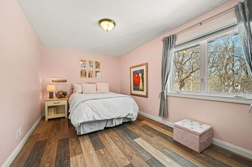 The 2nd main-level bedroom shines with modern LVT plank flooring and a spacious closet. A large window overlooks the beautiful backyard, filling the room with natural light. Perfect as a bright bedroom, nursery, or home office!