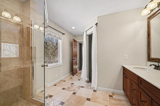 The best of both worlds! Enjoy backyard views from the large ensuite window while getting ready. This photo showcases the convenient walk-in closet and the bright, airy feel of the primary bath. Functional storage meets a beautiful, natural backdrop.