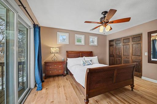 Imagine waking up to these wooded views! This angle showcases the large patio door that seamlessly blends your bedroom with the outdoors. Featuring gorgeous hardwoods and a spacious layout, this main-level retreat.
