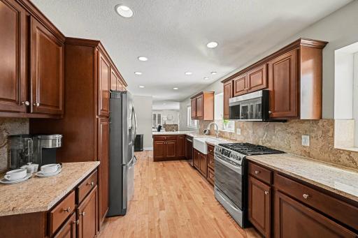This view of the kitchen shows the flow into the dining/living room. The stainless steel appliances are: Frigidaire gas stove with a griddle burner (2019), refrigerator (2020), microwave (2019) and a Maytag dishwasher (2023).