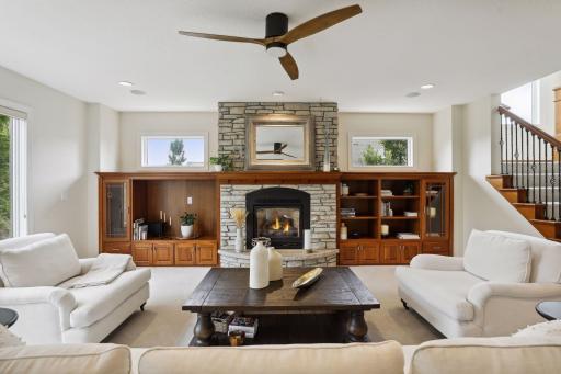 Sunlight pours through floor-to-ceiling windows in this spacious living room, where a cozy gas fireplace and custom built-ins create the perfect balance of warmth and elegance.
