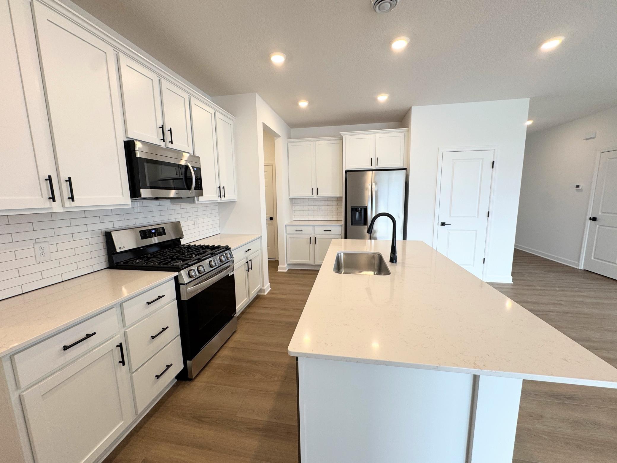 The multifunctional kitchen is equipped with brand-new stainless steel appliances, ample cabinetry storage and a center island that doubles as a breakfast bar.