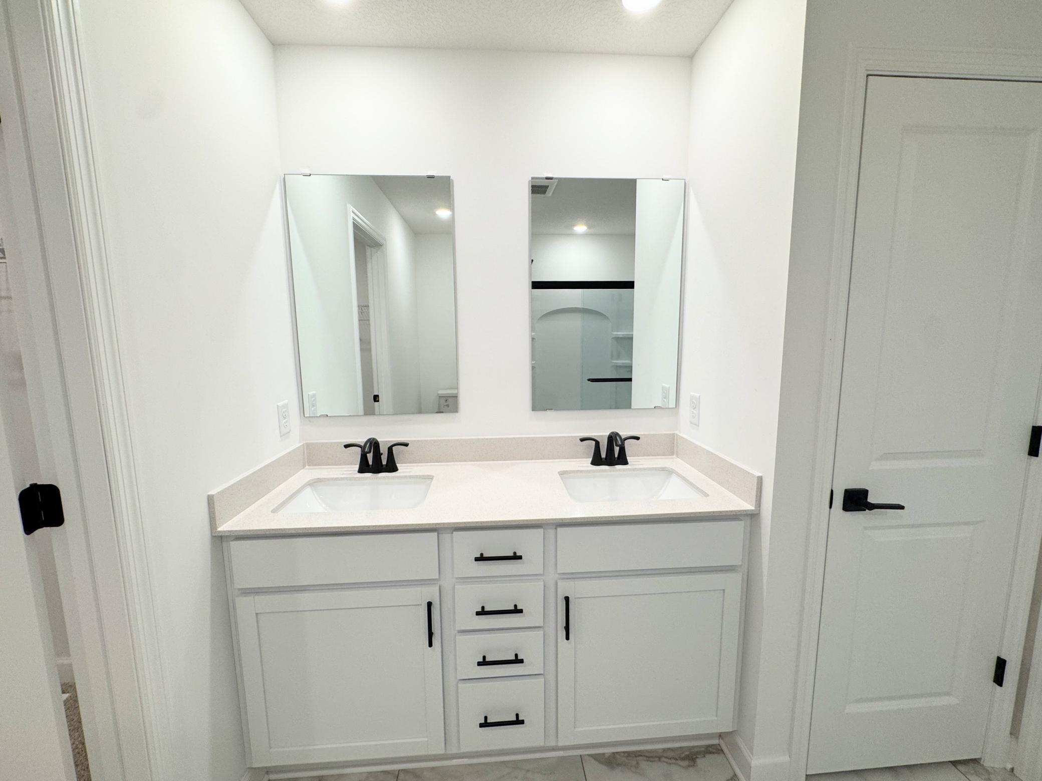 Dual sinks and mirror sit atop the stylish vanity to streamline everyday routines