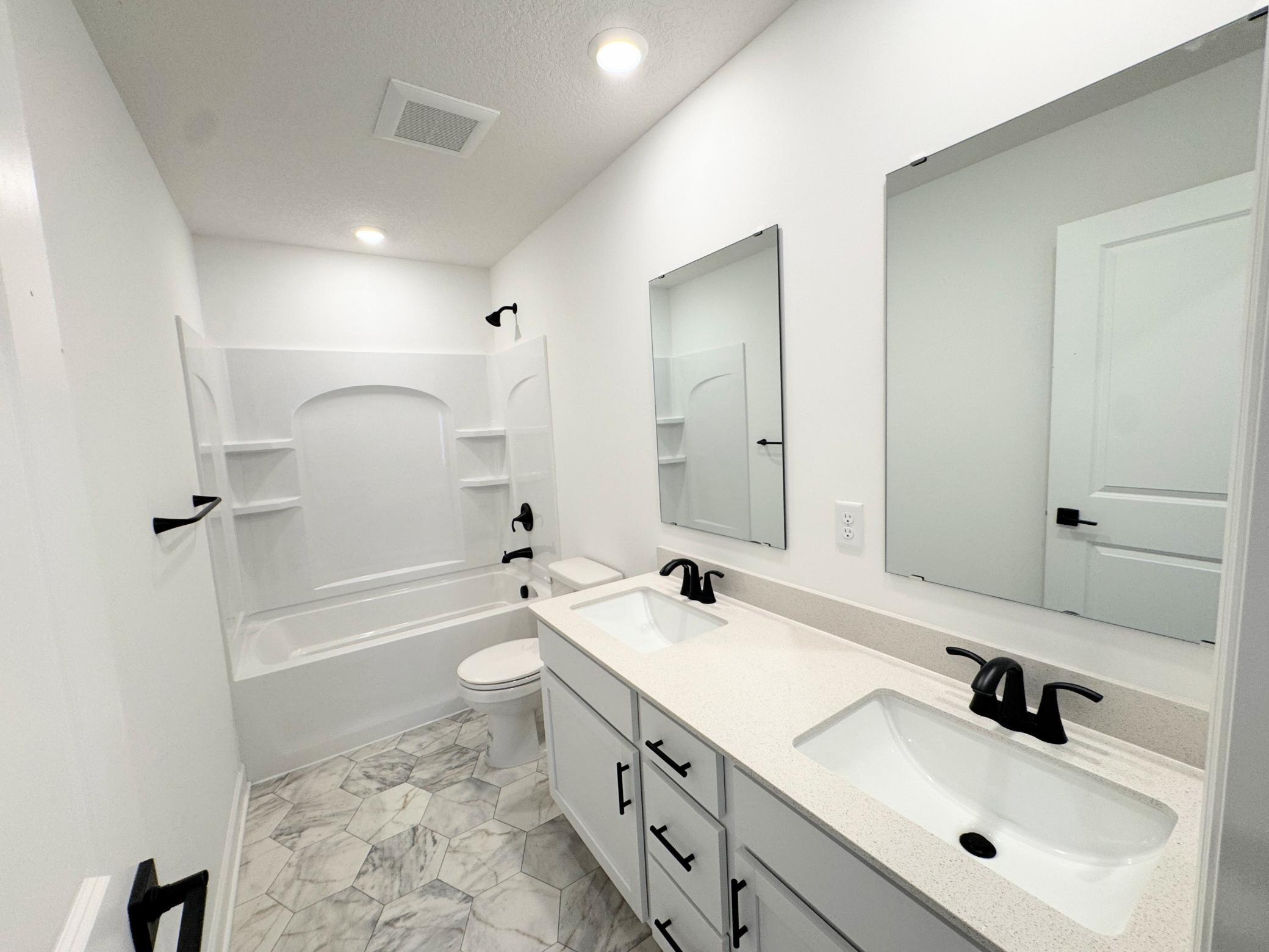 This shared full bathroom is equipped with convenient dual sinks and sleek designer plumbing fixtures.