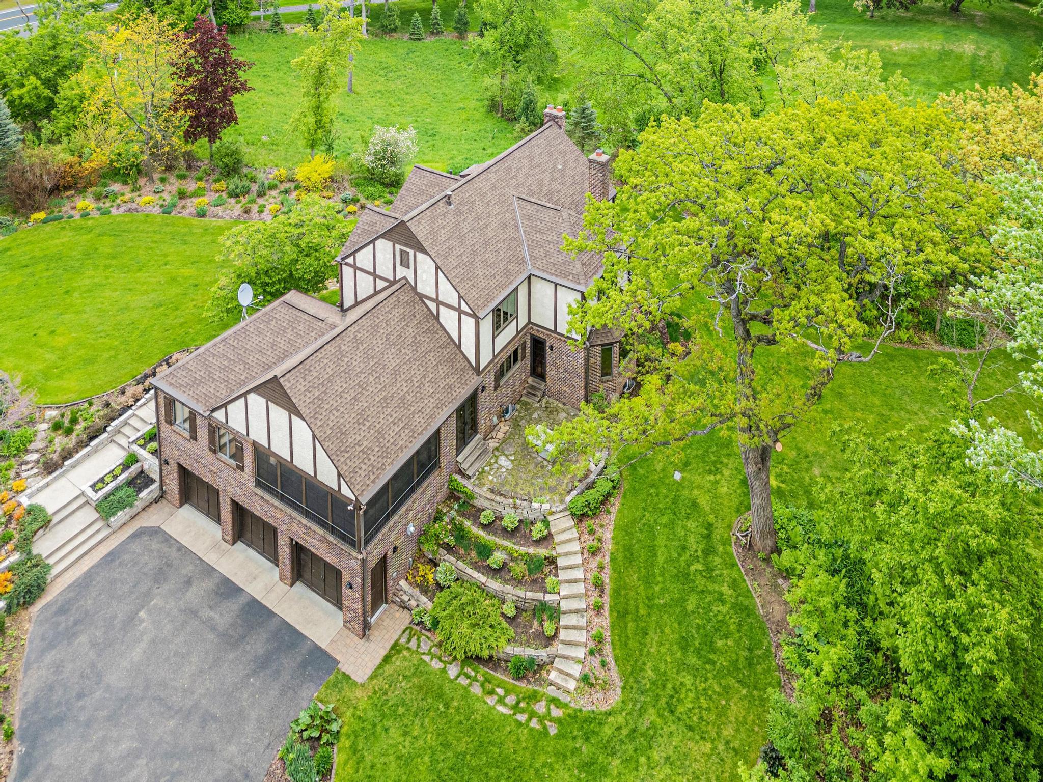 Stately curb appeal surrounded by mature trees, lush landscaping, and timeless stonework.