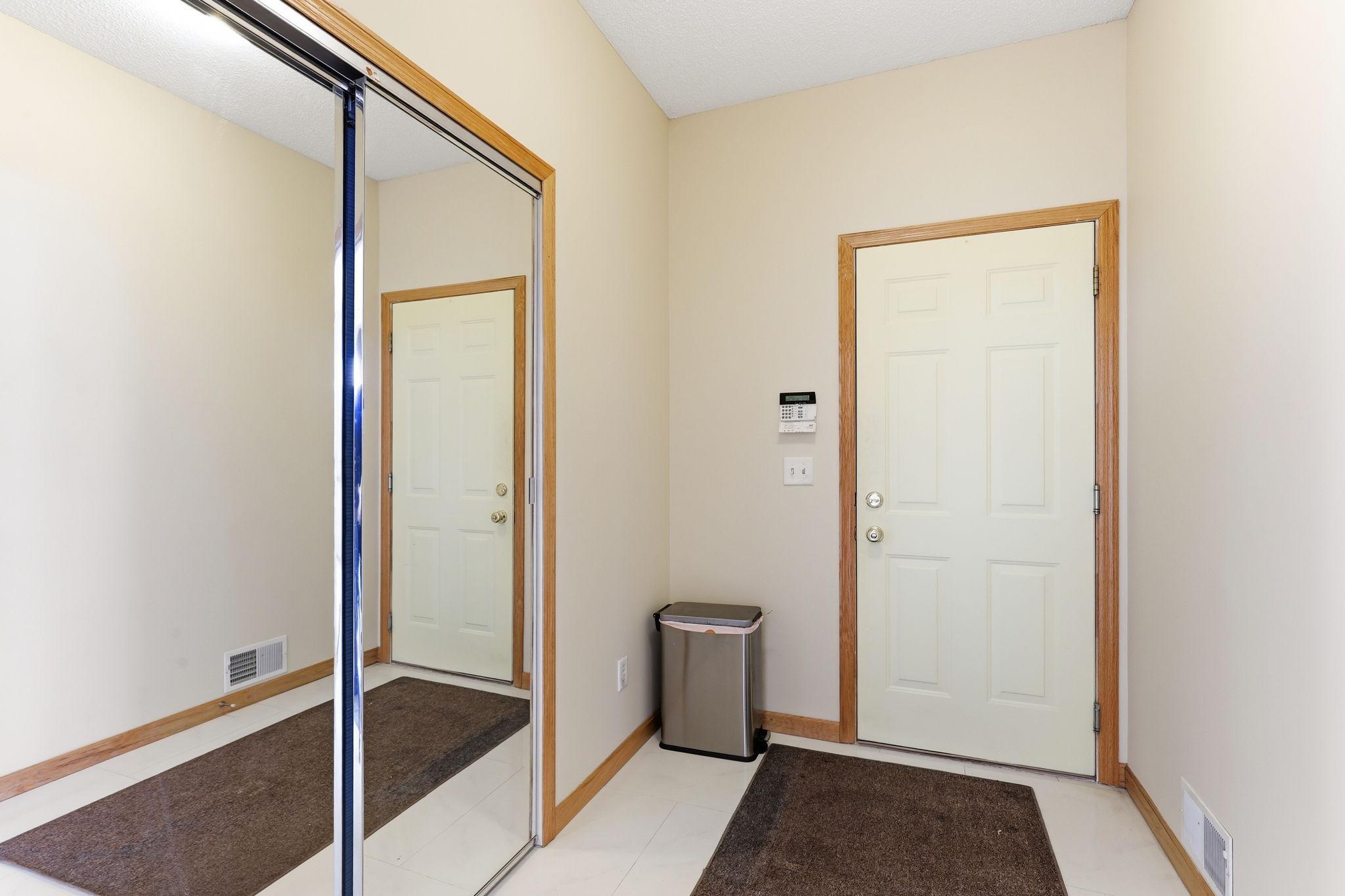 Hallway to 3 stall garage with mirror storage; spacious mudroom area