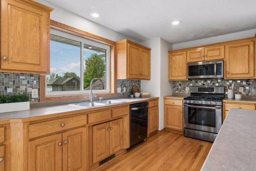 The beautiful black stainless steel appliances, hardwood floors, tiled backsplash and overhead recessed lighting complete this spacious kitchen.