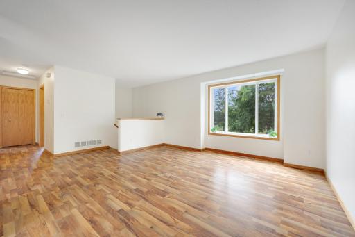 Main-level living room with a large window bringing in natural light and views of the trees outside