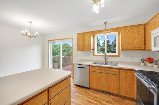 Kitchen workspace with the deck just beyond the sliding door and a window over the sink bringing in the view outside