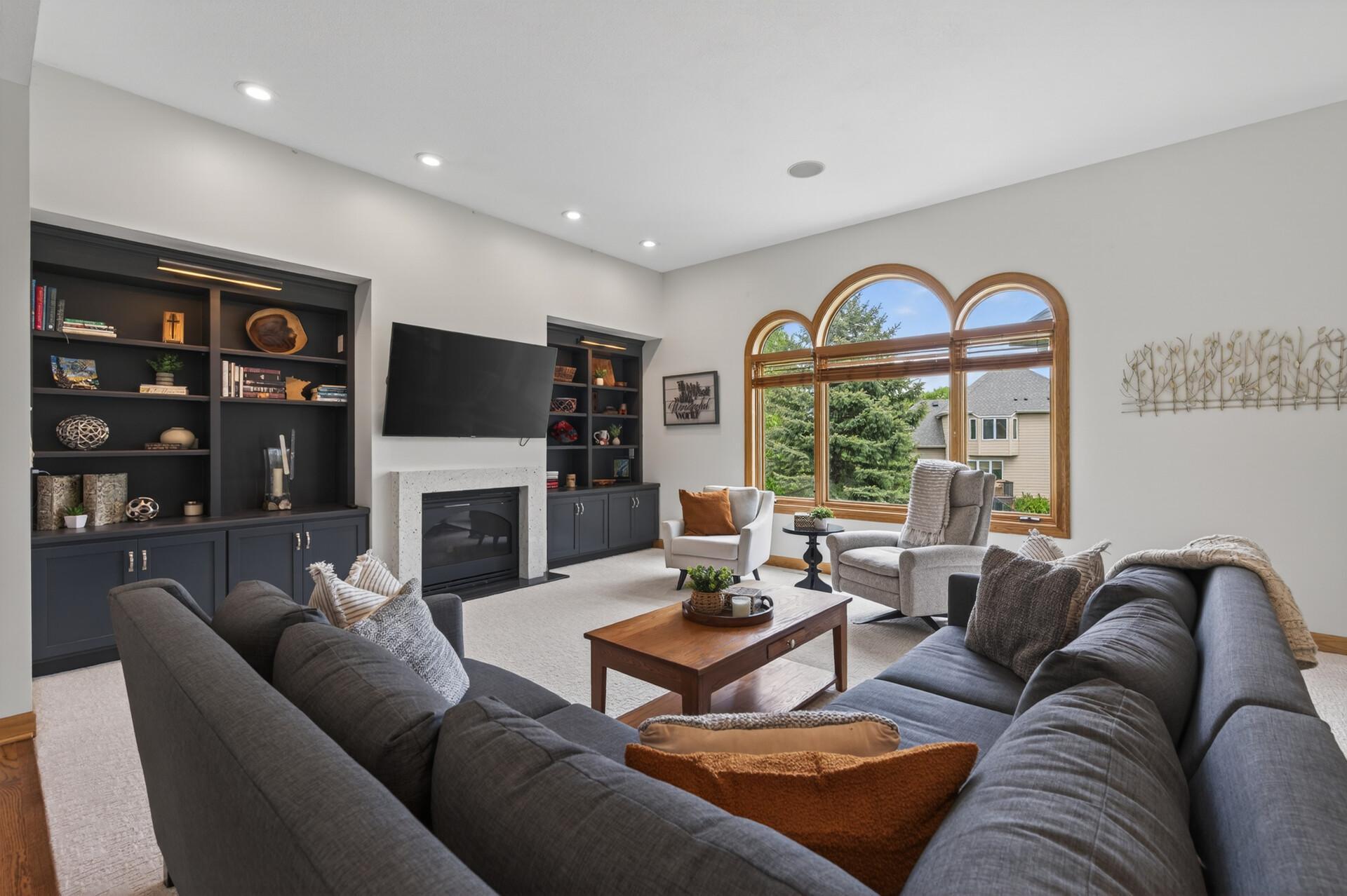 Living room with built-ins, gas fireplace, and large arched windows.