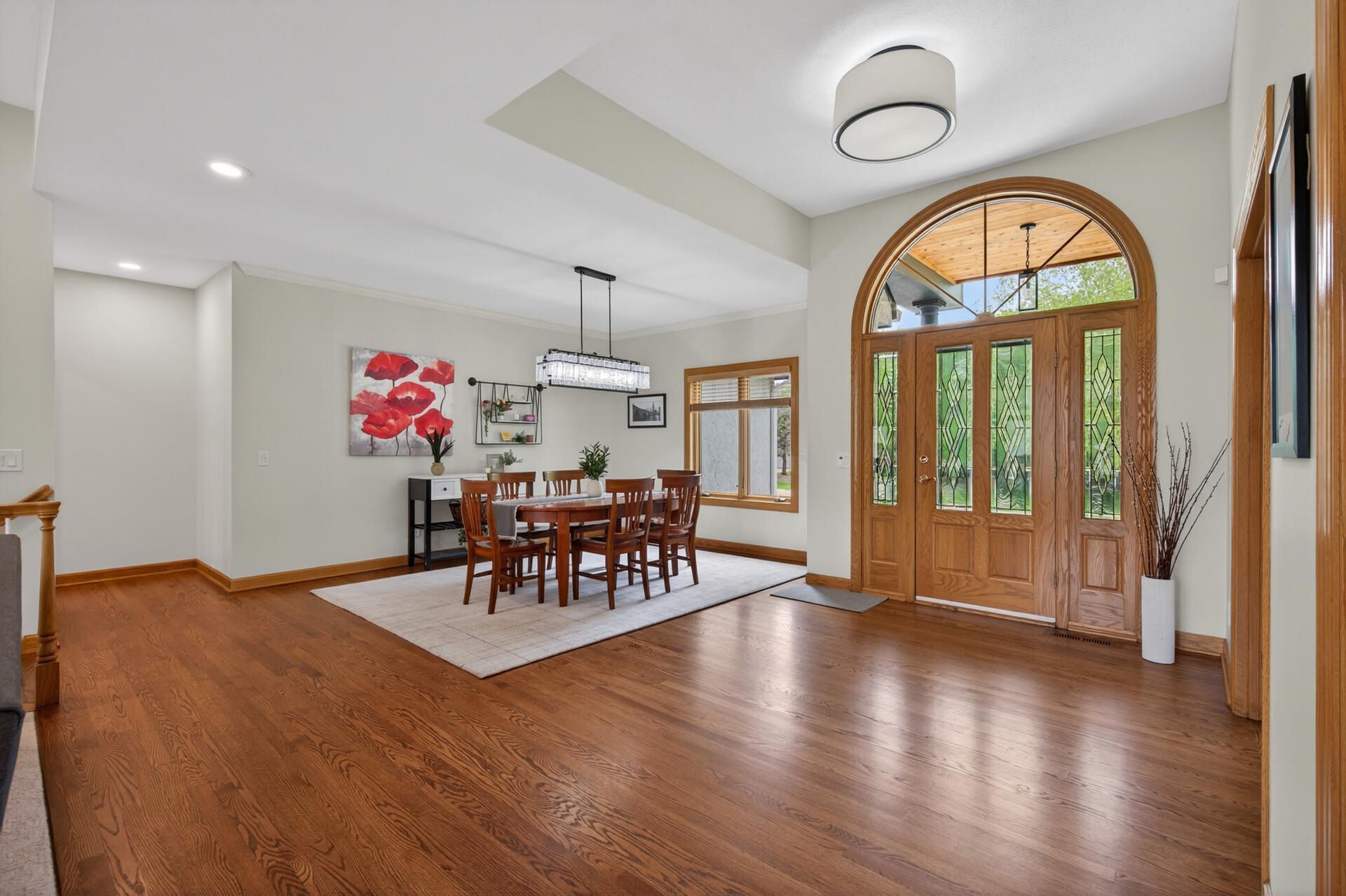 Open dining area and foyer with hardwood flooring and large windows.