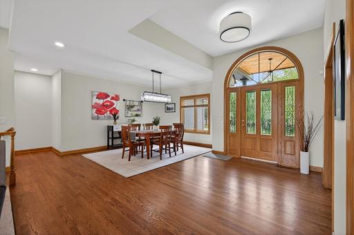 Open dining area and foyer with hardwood flooring and large windows.