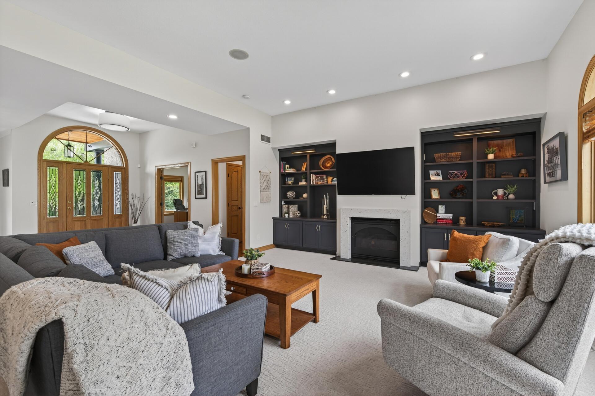 Spacious living room with built-in cabinetry, gas fireplace, and soaring ceilings.