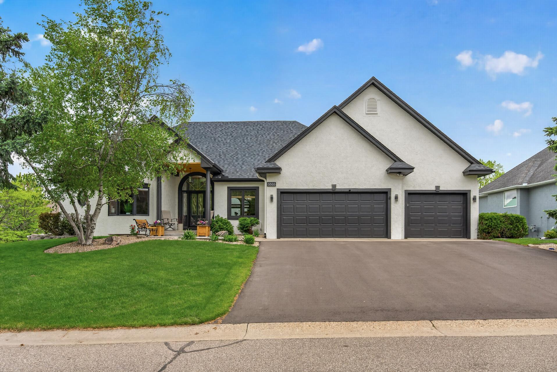 Spacious front exterior with mature trees and oversized driveway.