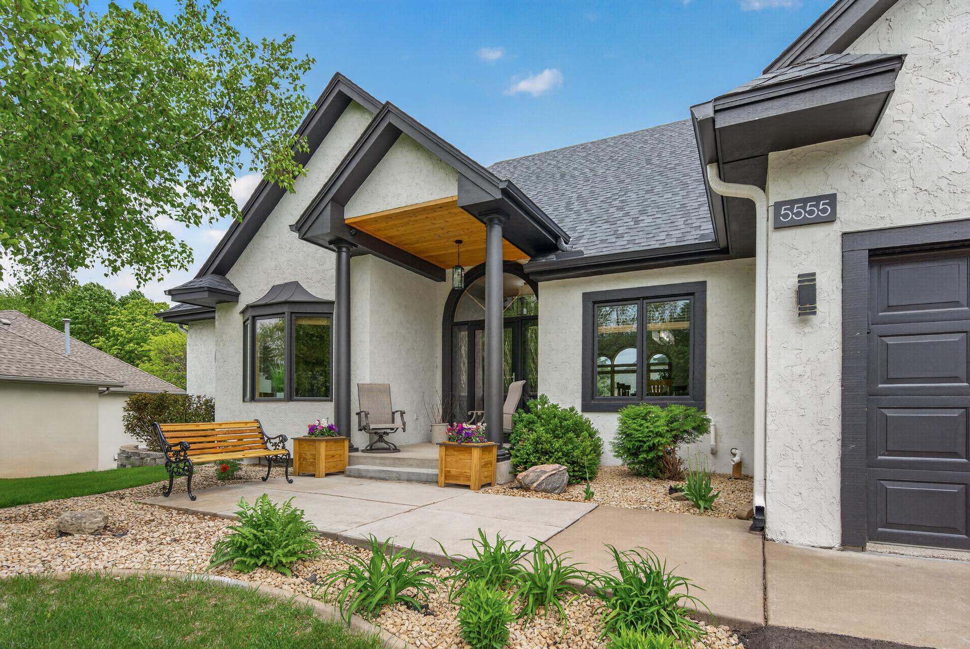 Covered front porch with cedar ceiling detail and landscaped entry.