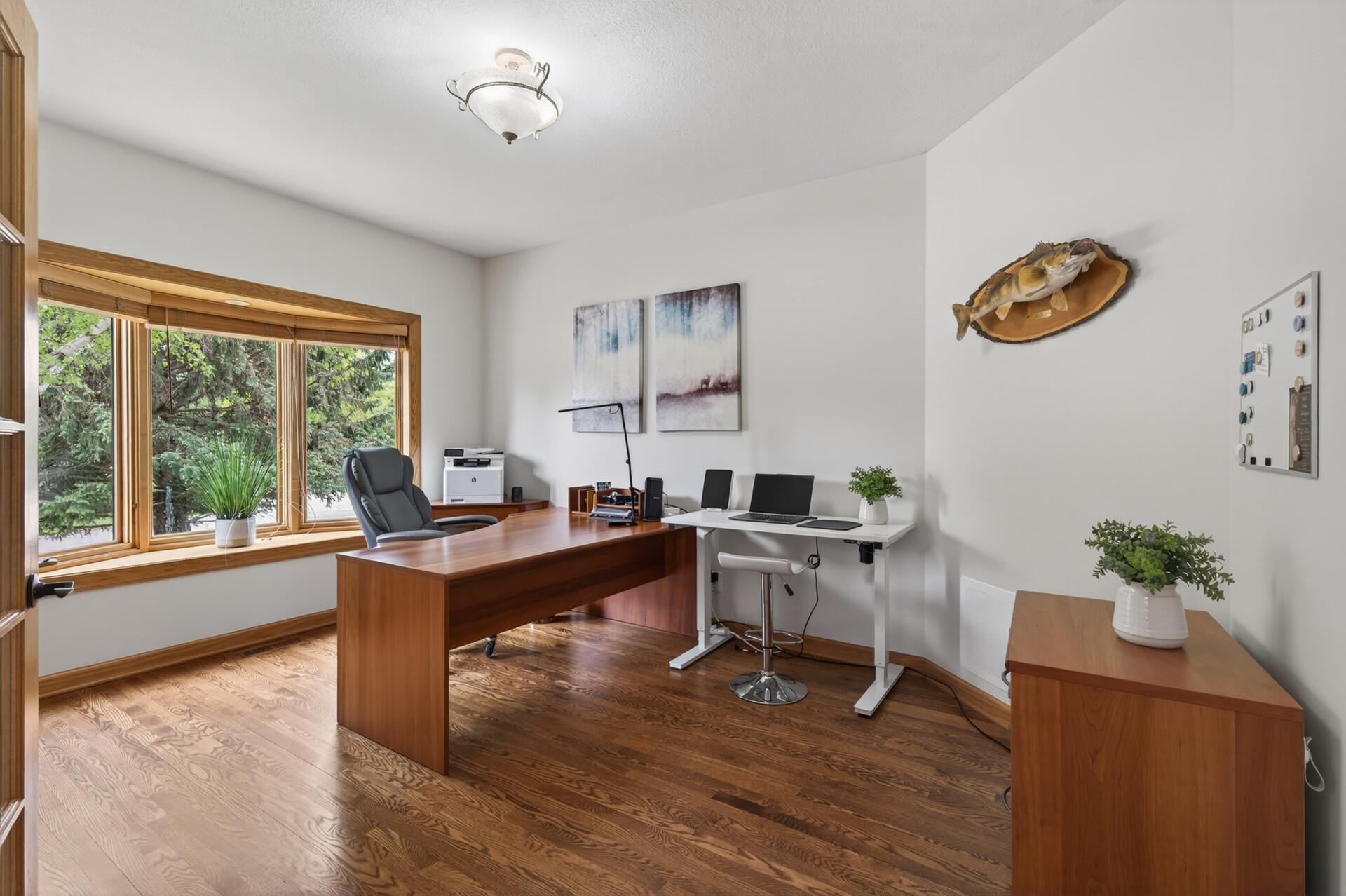 Main level office with hardwood floors, large picture window, and flexible workspace.