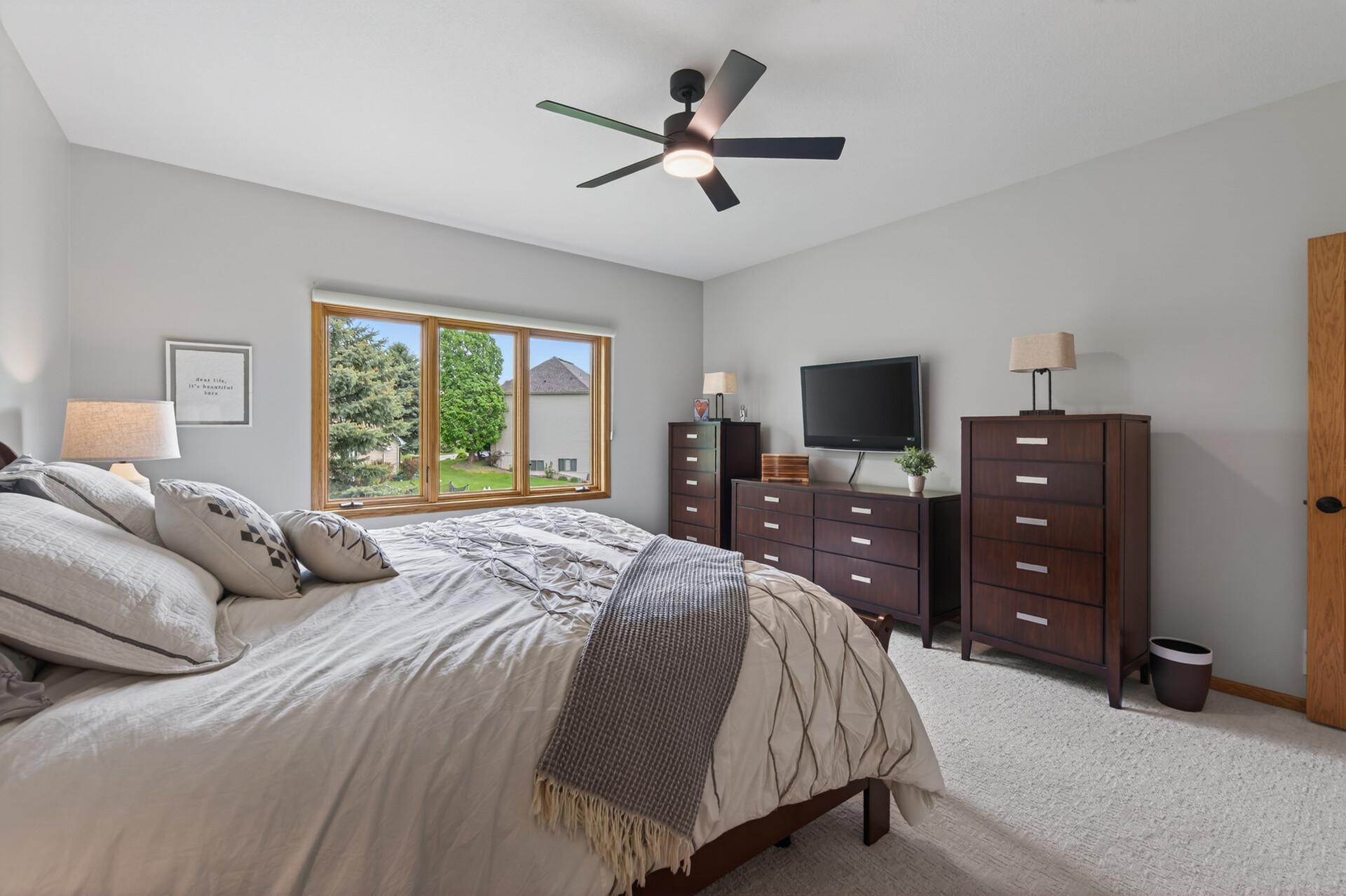 Primary suite with generous layout, updated ceiling fan, and ample furniture space.