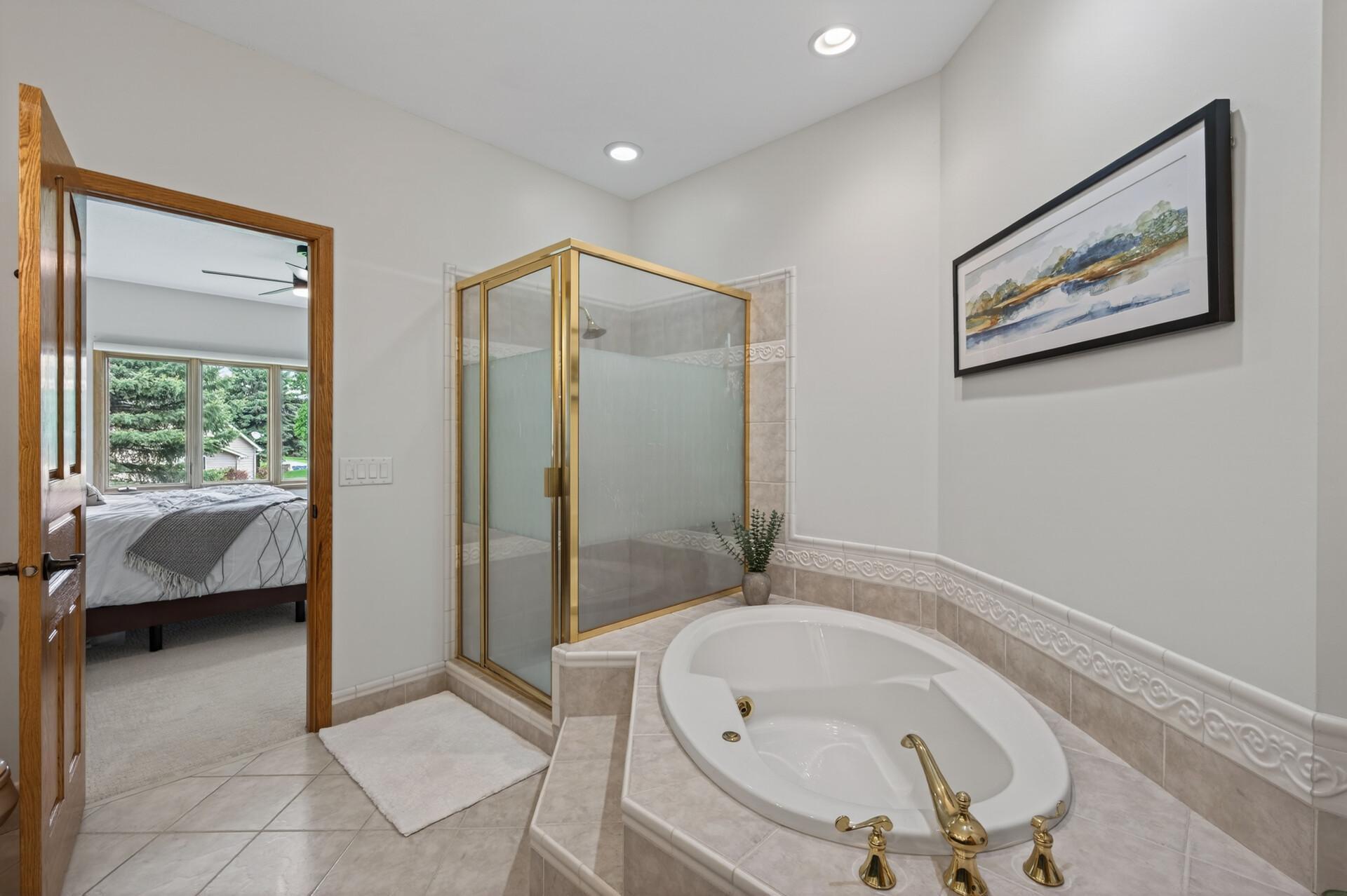 Spacious primary bath with separate shower, whirlpool tub, and private ensuite access.