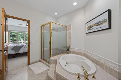 Spacious primary bath with separate shower, whirlpool tub, and private ensuite access.