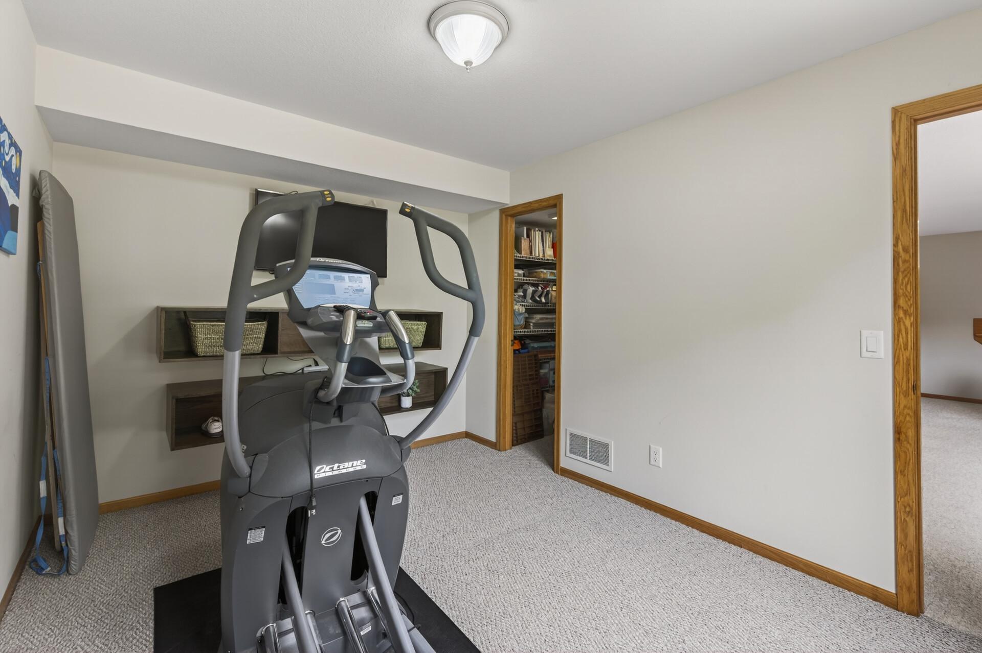 Versatile lower-level exercise or flex room with adjacent storage access.