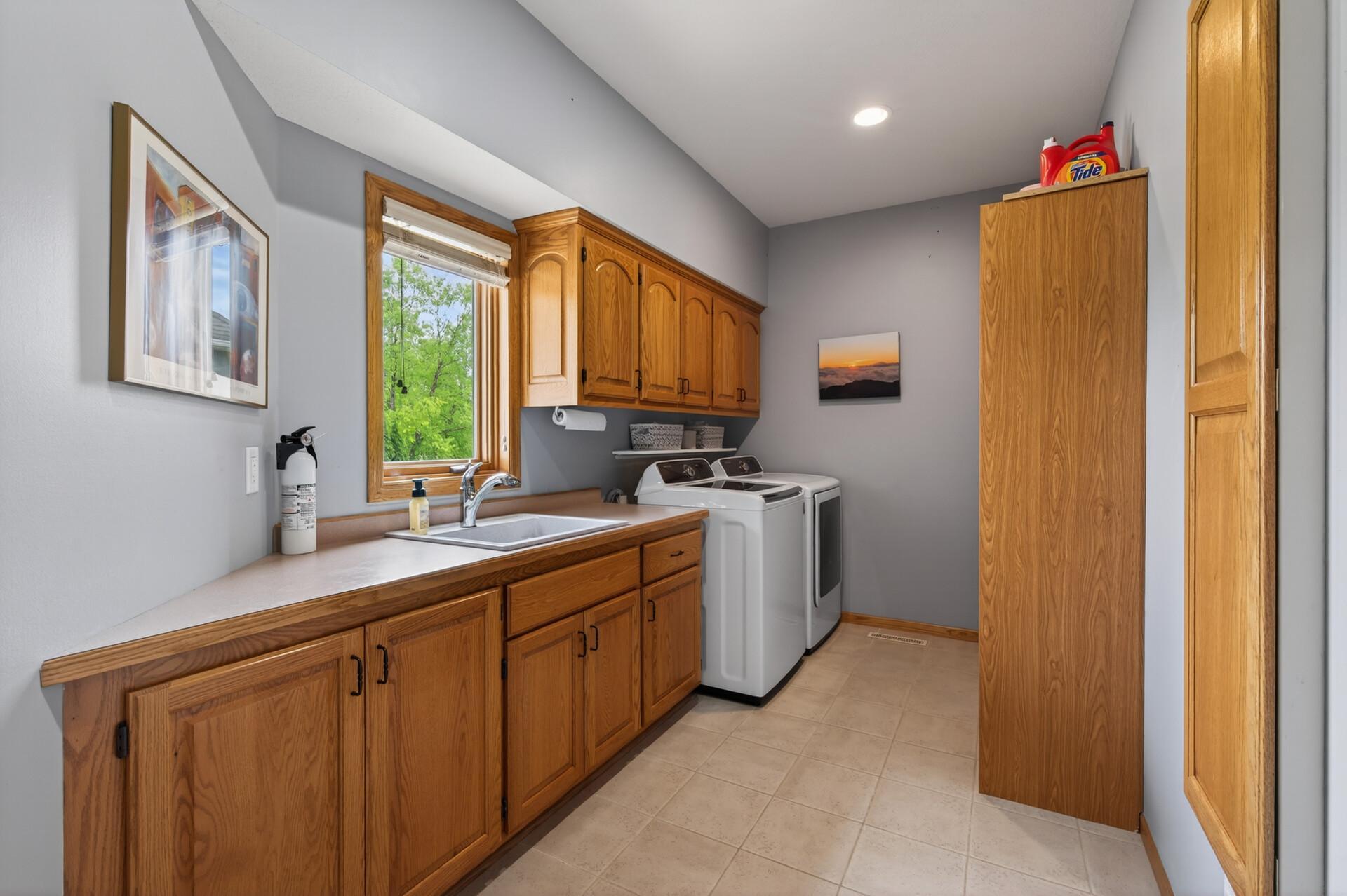 Spacious laundry room with abundant cabinetry, utility sink, and natural light.