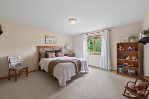 Spacious upper-level bedroom with neutral finishes, large window, and generous floor space.