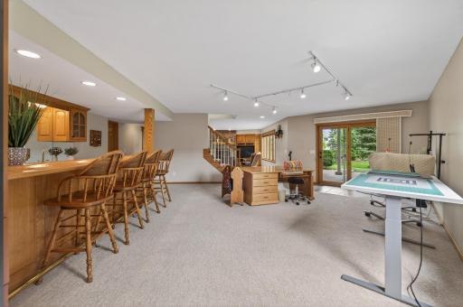 Expansive lower-level recreation room with full wet bar, workshop space, and walkout to backyard patio.