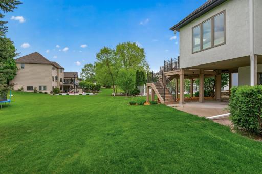 Private backyard retreat featuring a large lawn, mature trees, and walkout lower level access.