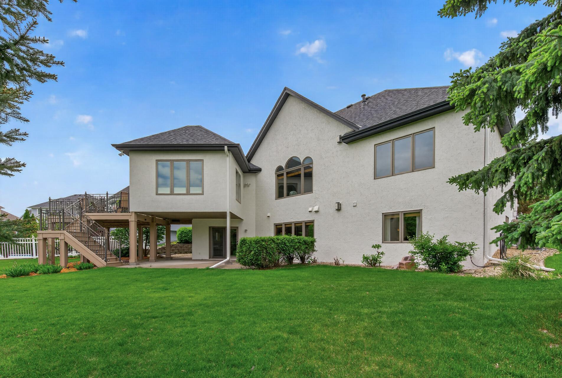 Impressive backyard with expansive lawn, mature landscaping, and walkout access beneath the deck.