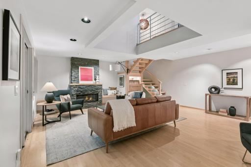 Open-concept living room features a dramatic stone fireplace and vaulted ceiling.