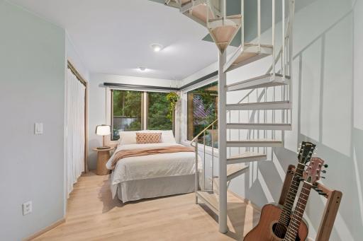 A very special bedroom with a private spiral staircase and wooded views