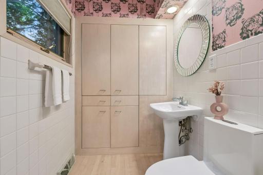 A playful powder room adds personality with bold patterned wallpaper and classic tile.
