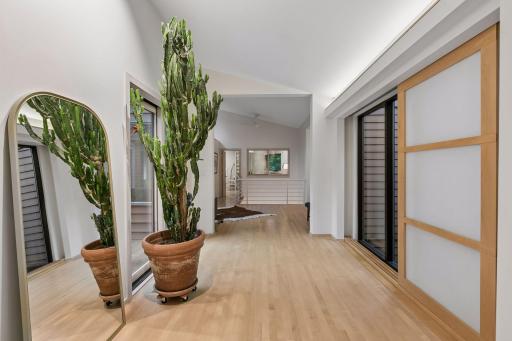 Bright open hallway with hardwood floors, expansive windows, and clean-lined architectural details.