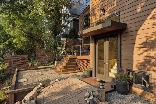 Inviting outdoor entry with tiered deck, natural stone and mature landscaping.