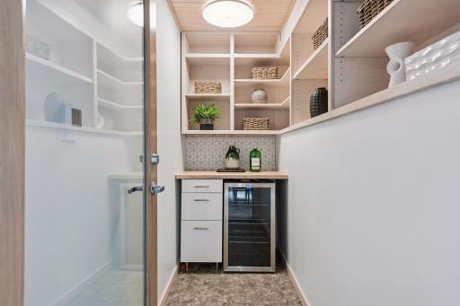Thoughtfully designed pantry with custom built-ins, beverage refrigerator and tile backsplash.
