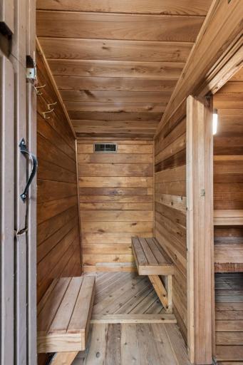 Warm cedar sauna interior with built-in benches and traditional sauna heater.
